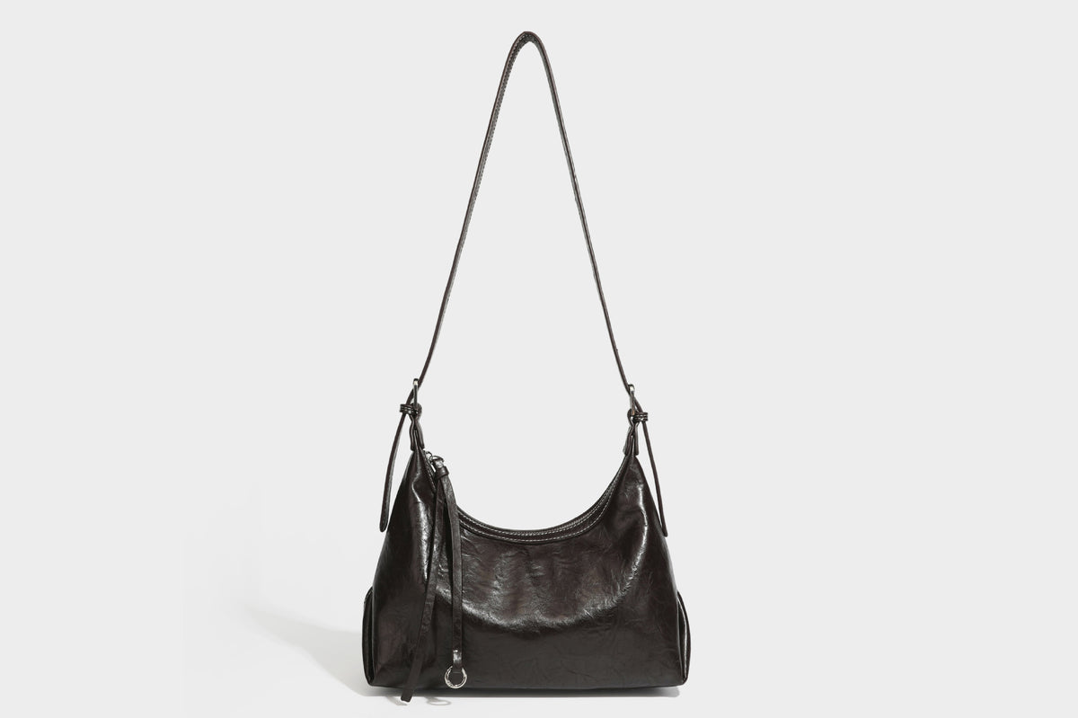 Slouchy hobo shoulder bag in glossy crinkled leather-look finish with zip-top closure and silver-tone ring hardware, detail