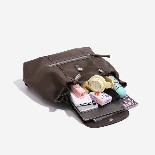 Large flap-top nylon backpack with leather-look trim, snap closure, front zip pocket, and padded shoulder straps, detail view