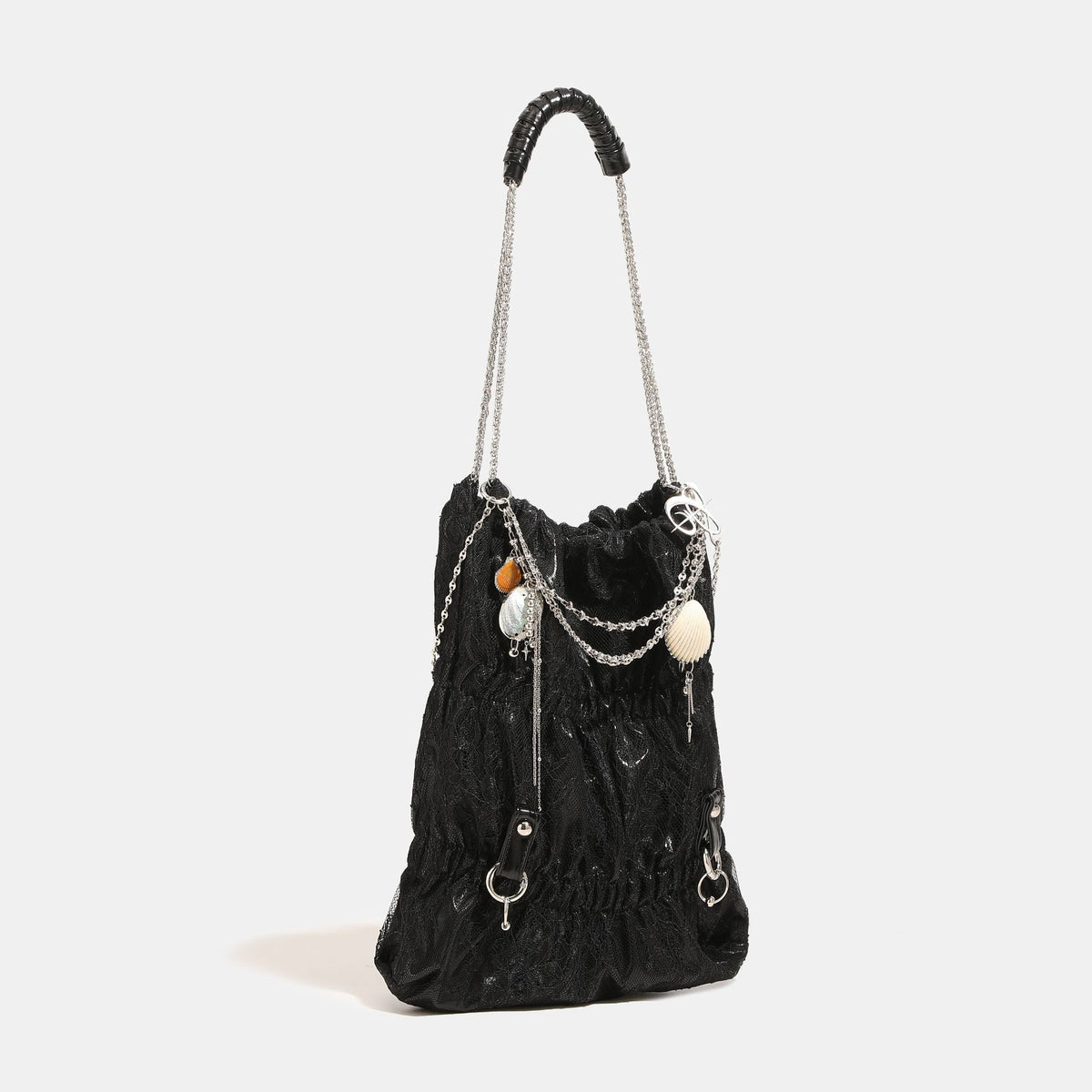 Slouchy lace-overlay bucket bag with silver chain strap, draped chain detail, shell charms, and drawstring top closure