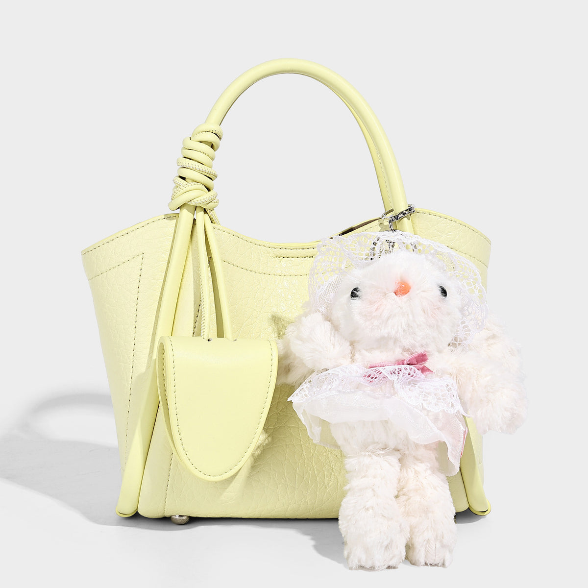 Structured mini tote bag in pebbled leather-look finish with knotted top handles, front flap pocket, and detachable shoulder