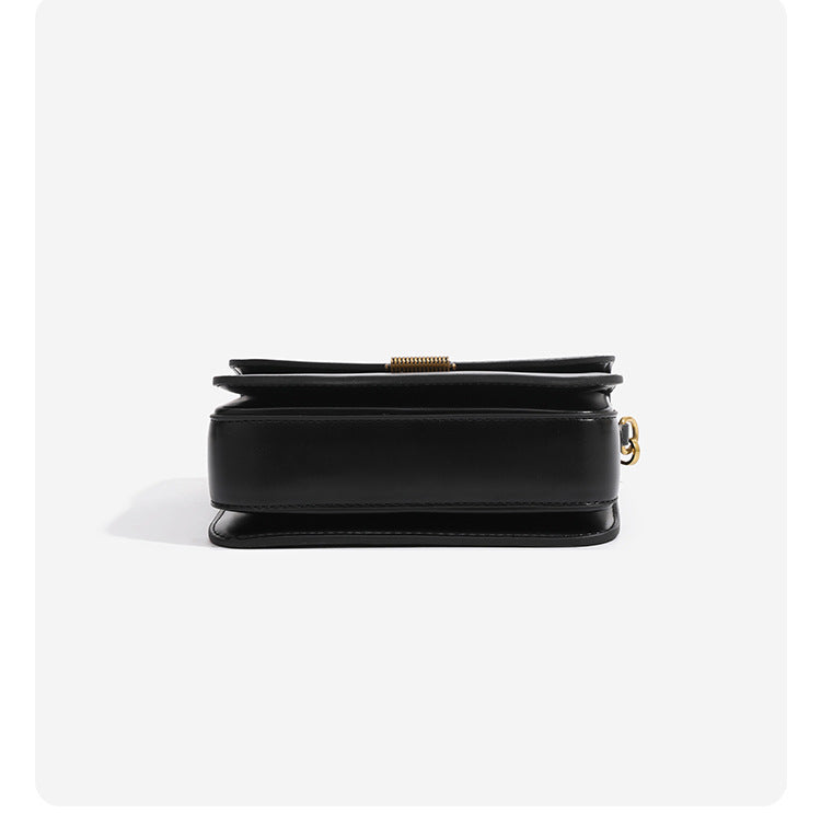 Mini structured black flap crossbody bag with gold-tone ribbed rectangular clasp and adjustable shoulder strap, detail view