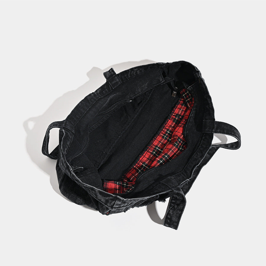 Large washed black distressed denim tote bag with white spider web embroidery and red spider motifs on the front panel