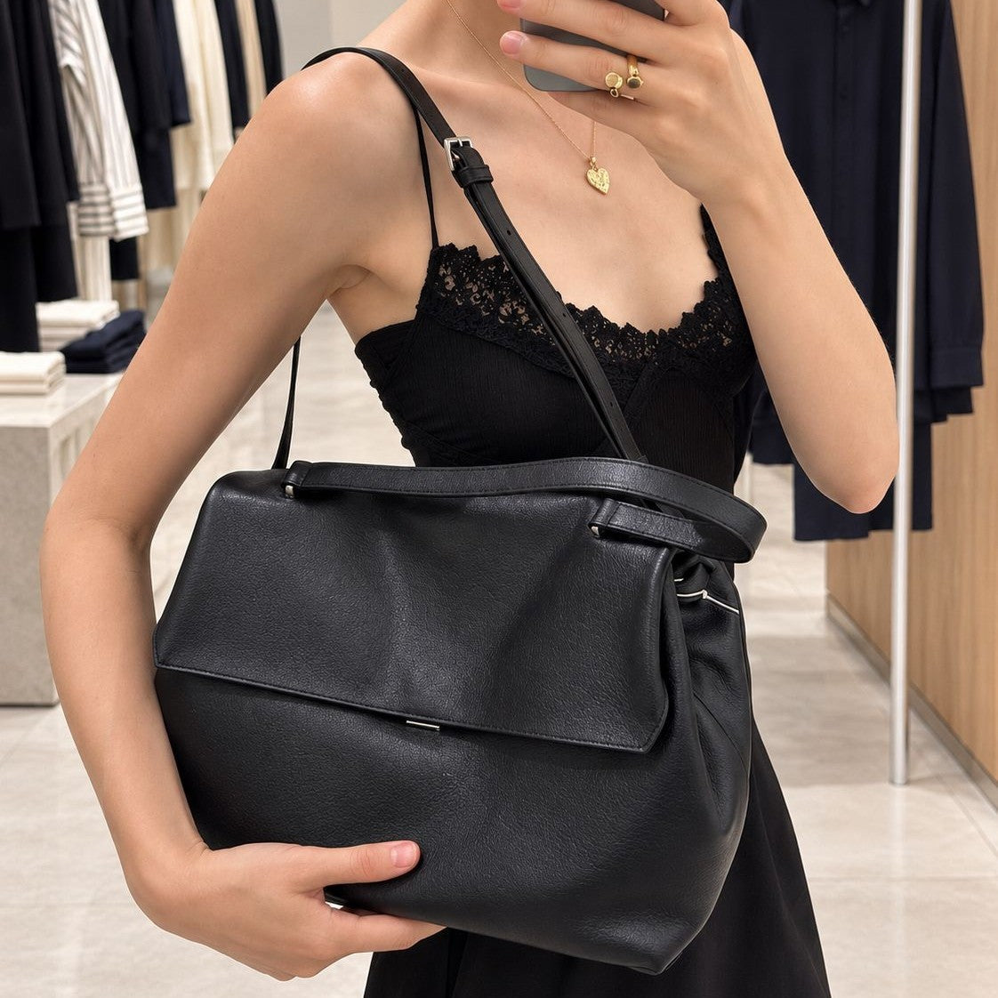 Large black slouchy leather-look shoulder bag with V-shaped envelope flap, silver-tone clasp, and adjustable strap, front