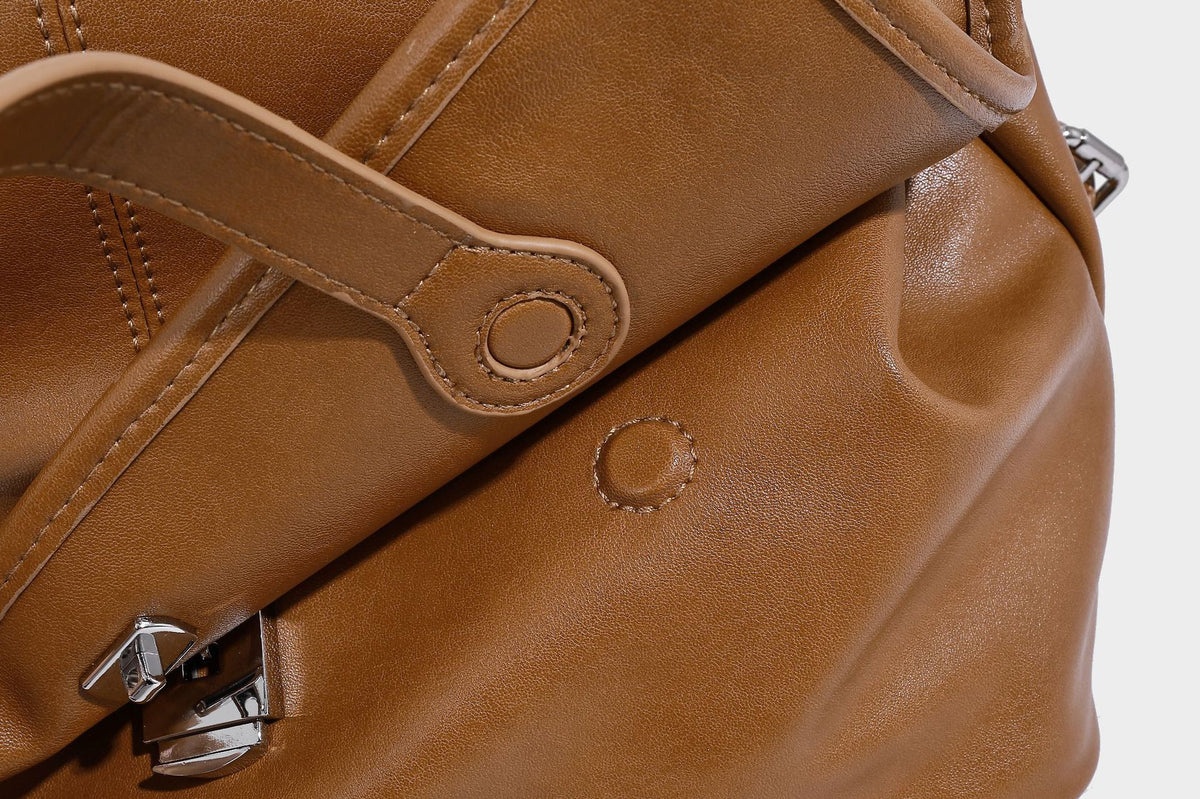 Structured tan leather-look flap backpack handbag with top handle, silver buckle hardware, and fold-over front closure