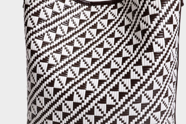 Geflochtene Schultertasche mit geometrischem Ethno-Muster, Besatz in dunkelbrauner Lederoptik, langem verstellbarem Träger und kleinem hängendem Reißverschluss