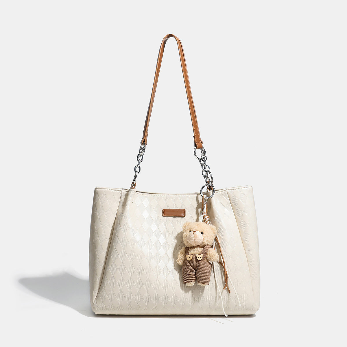 Black diamond-quilted leather-look tote bag with silver chain-ring shoulder straps and plush bear charm pendant, detail view