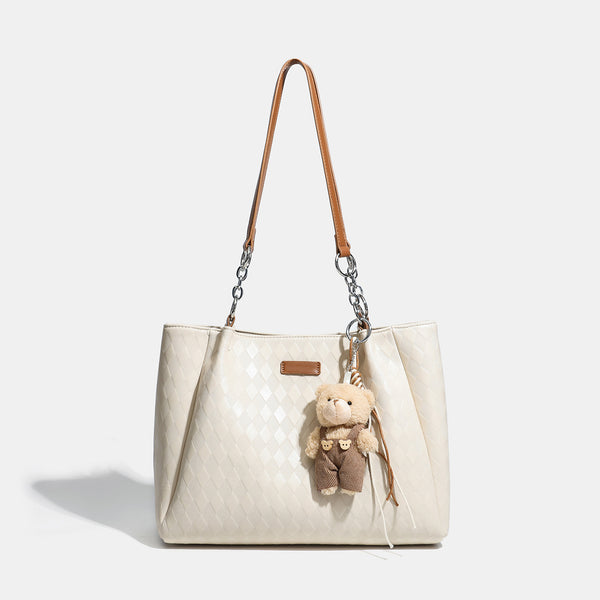 Black diamond-quilted leather-look tote bag with silver chain-ring shoulder straps and plush bear charm pendant, detail view