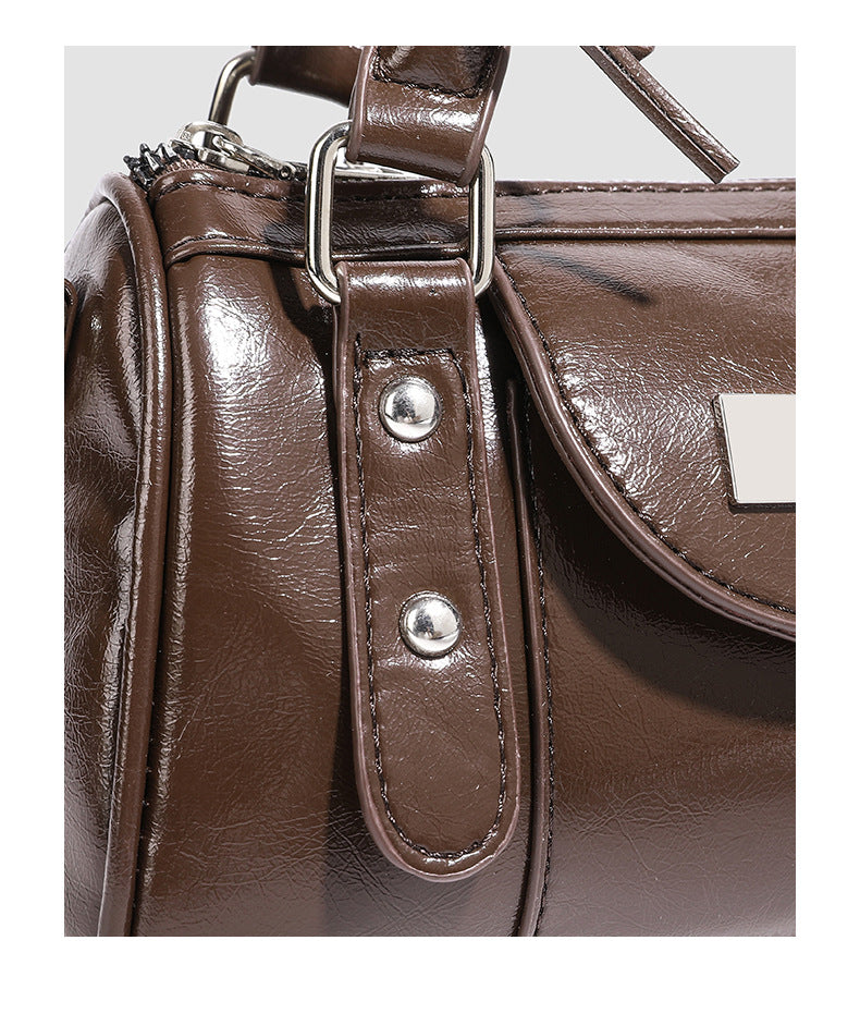 Kleine strukturierte Henkeltasche in glänzender Lederoptik mit Schleifen verzierten Henkeln und Vordertasche mit Herzverschluss, Detail