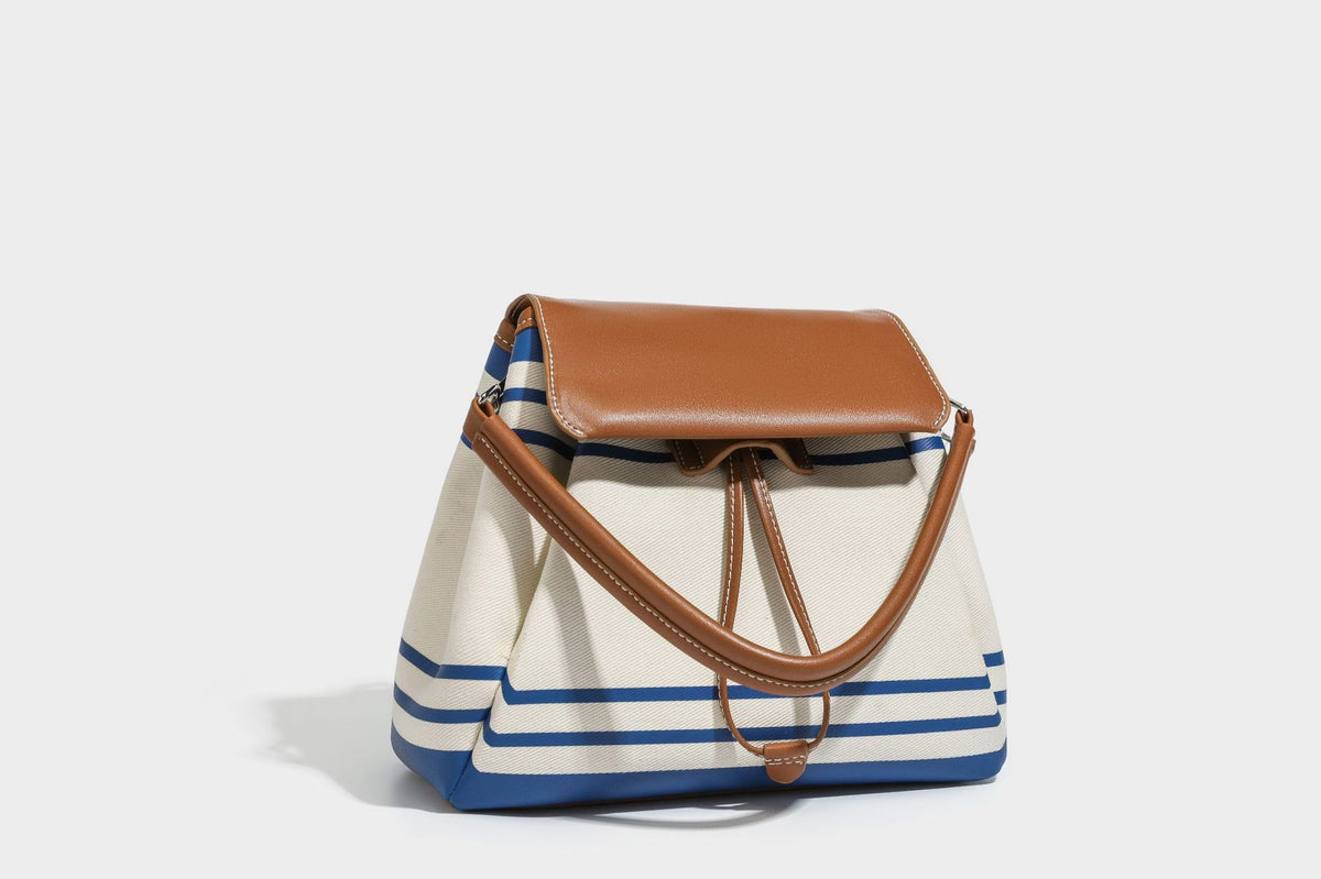 Cream canvas bucket bag with blue horizontal stripes, tan leather-look flap and trim, drawstring closure, silver-tone, detail