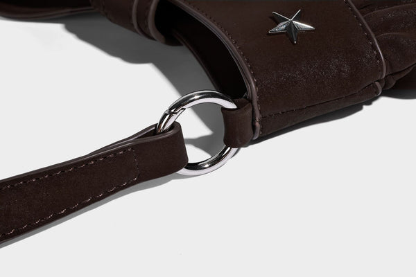 Ruched shoulder bag with curved flap, silver star studs, dangling starfish charm, and adjustable crossbody strap, detail view