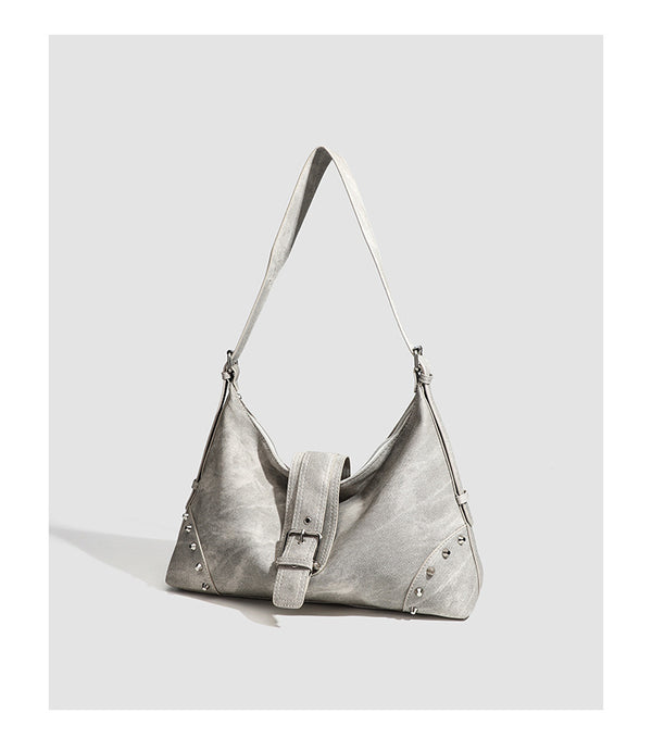 Slouchy trapezoid hobo shoulder bag with distressed textured finish, silver rivet corner accents, centre buckle strap, and
