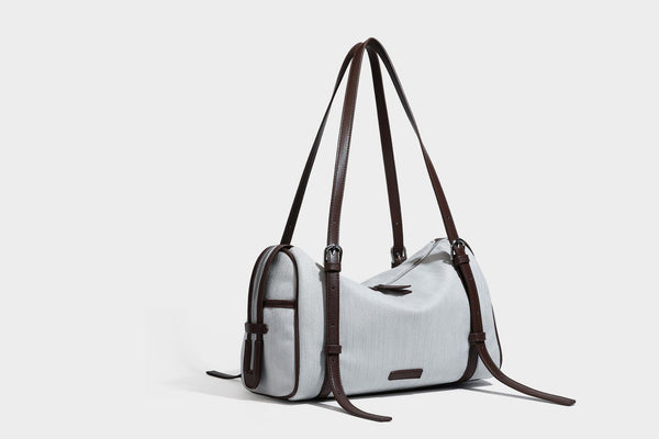 Olivgrüne Schultertasche in Zylinderform aus Canvas mit Riemen in schwarzer Lederoptik, Reißverschluss oben und silberfarbenen Beschlägen, Detailansicht