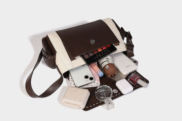 Structured flap crossbody bag in dark brown and cream color-block with white contrast stitching, adjustable shoulder strap