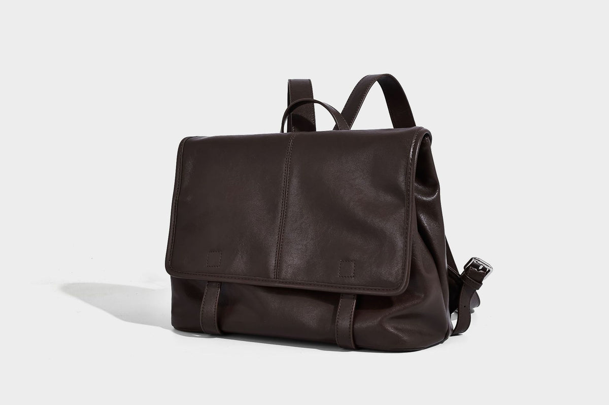 Structured tan leather-look flap backpack handbag with top handle, silver buckle hardware, and fold-over front closure