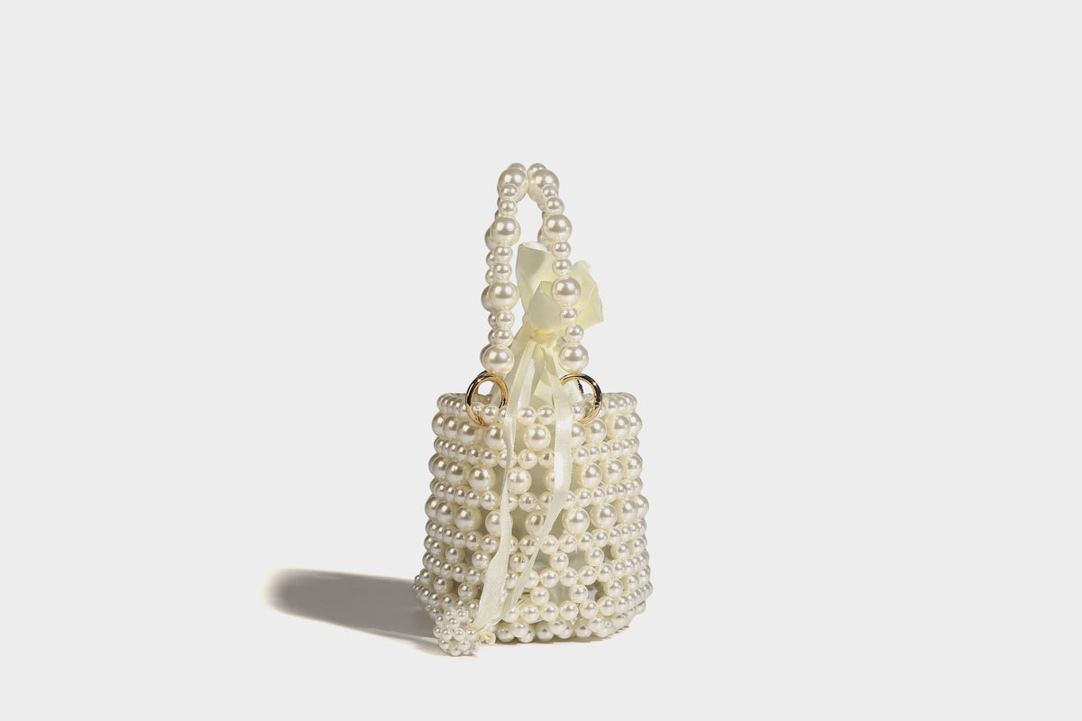 Elfenbeinfarbene Mini-Bucket-Bag aus Kunstperlen mit Satin-Innenbereich und Zugband, goldfarbenen Ringbeschlägen und gewölbtem Perlenhenkel an der Oberseite