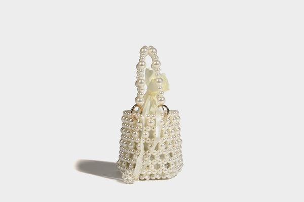 Elfenbeinfarbene Mini-Bucket-Bag aus Kunstperlen mit Satin-Innenbereich und Zugband, goldfarbenen Ringbeschlägen und gewölbtem Perlenhenkel an der Oberseite