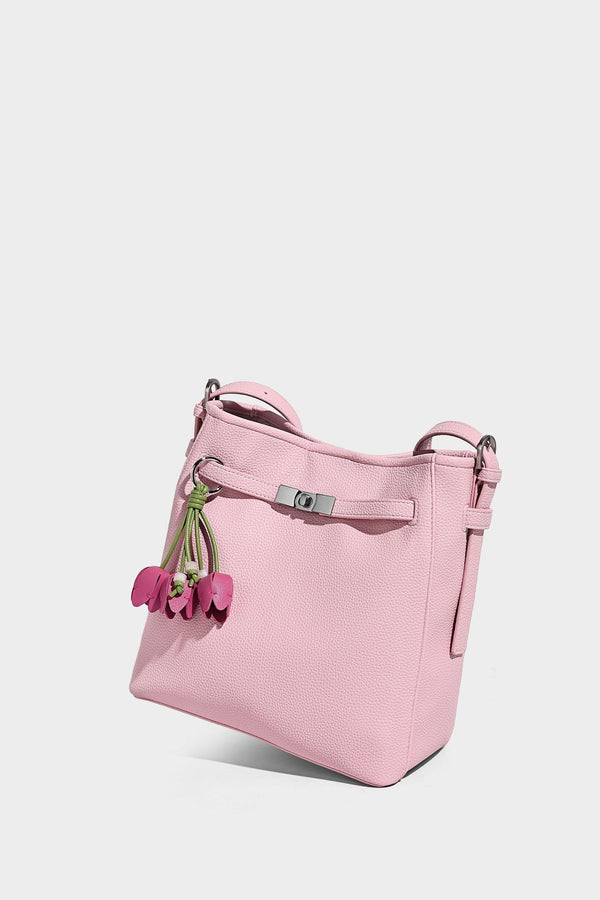 Soft-structured pebbled bucket shoulder bag with front turn-lock strap detail, adjustable strap, and hanging floral tassel