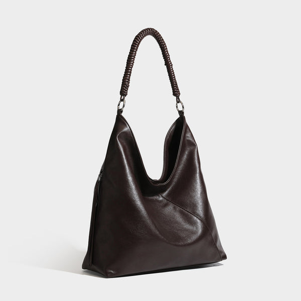 Large slouchy hobo shoulder bag with braided top handle, smooth glossy leather-look finish, and silver-tone ring hardware