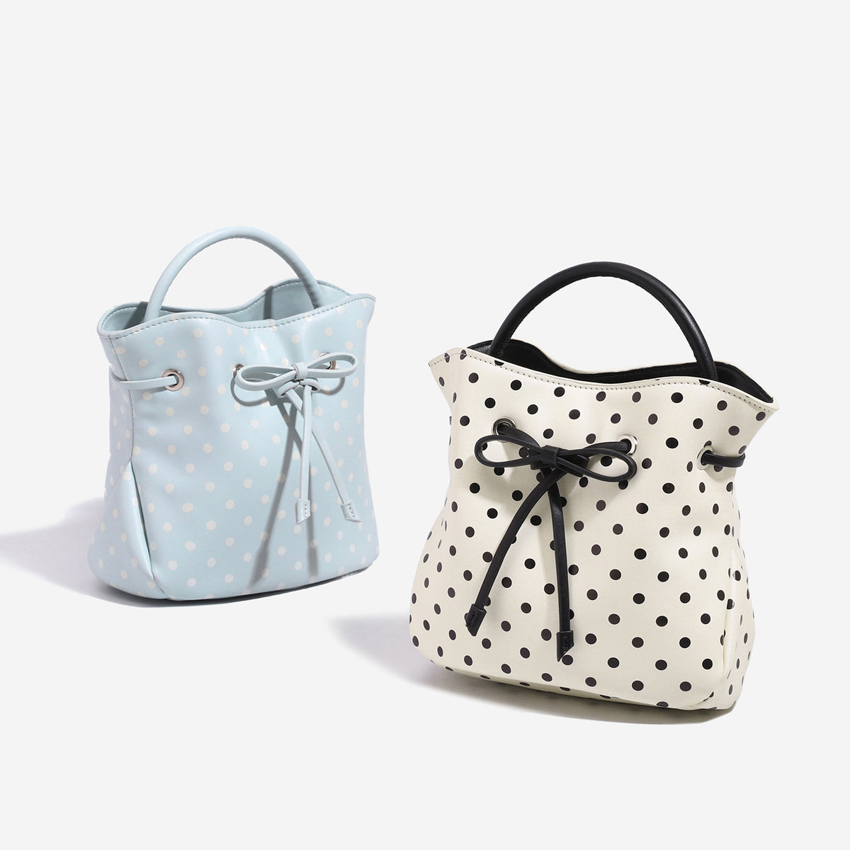 Cream white polka-dot drawstring bucket bag with black leather-look top handle and bow-tied cord closure, detail view 2