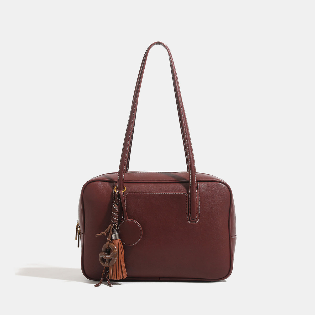 Structured rectangular leather-look shoulder bag with top zip, tassel and resin ring charm, and contrast topstitching, detail