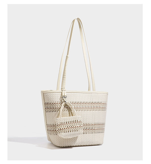 Large structured woven tote bag with striped basket-weave finish, long shoulder straps, and detachable mini pouch charm