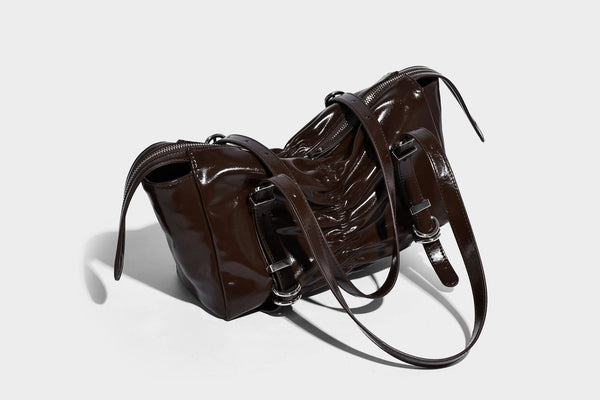 Glänzende, rechteckige Schultertasche mit Raffdetails, zwei verstellbaren Riemen, Reißverschluss oben und Schnallenbeschlägen in Silberoptik
