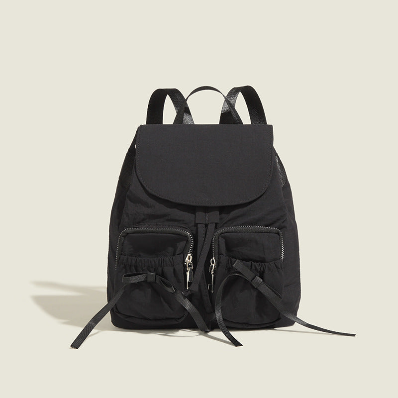 Soft matte nylon drawstring backpack with ruched bow-detail front zip pockets, top carry handle, and silver-tone hardware