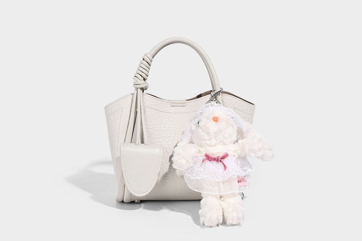 Structured mini tote bag in pebbled leather-look finish with knotted top handles, front flap pocket, and detachable shoulder