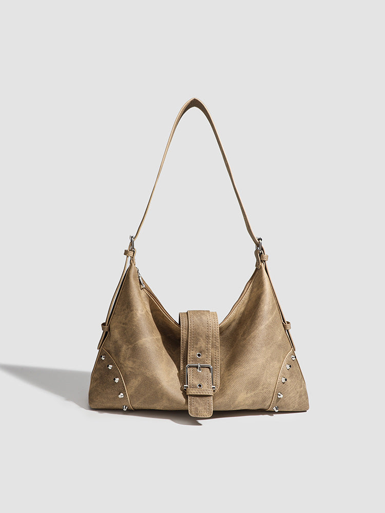 Slouchy trapezoid hobo shoulder bag with distressed textured finish, silver rivet corner accents, centre buckle strap, and