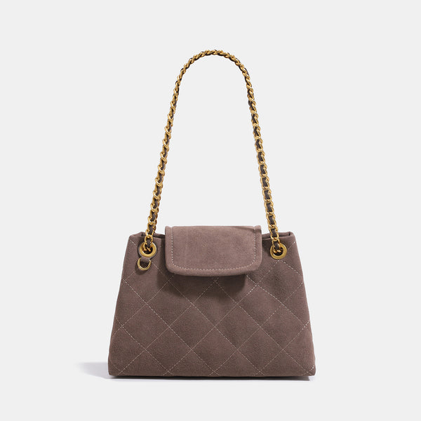 Quilted trapezoid shoulder bag with chain straps, flap closure, and ring hardware, front view