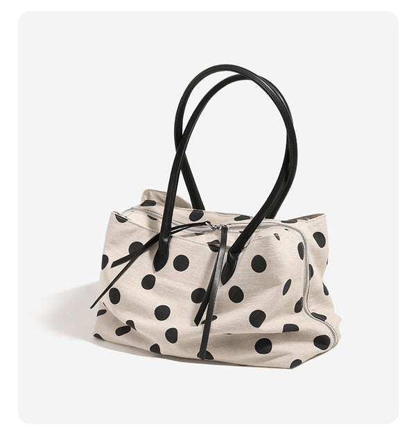 Cream canvas tote bag with black polka dots, rounded leather-look handles, and zip-top closure, detail view 9