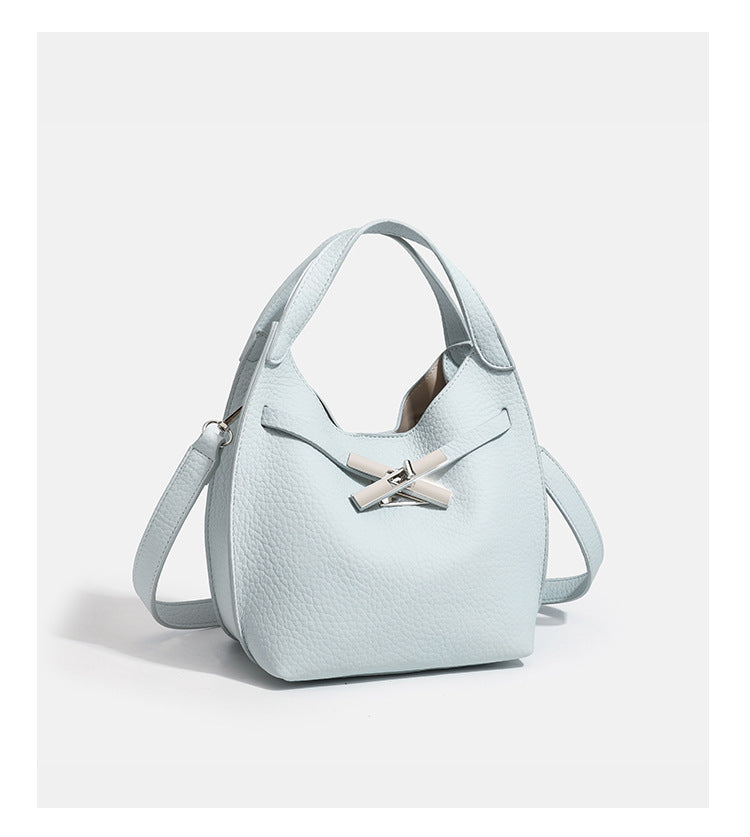 Compact pebbled leather-look shoulder bag with crossed silver-toned metal front closure, short top handle, and long, detail
