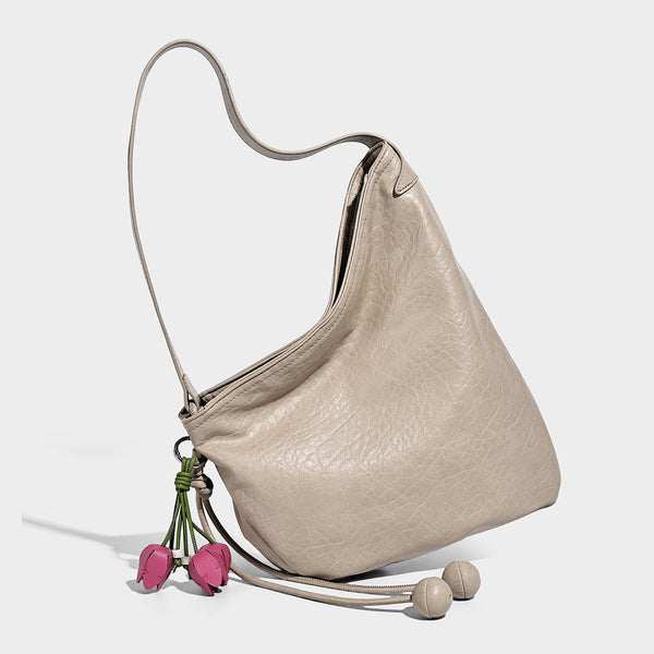 Slouchy hobo shoulder bag in pale yellow with slim strap, drawstring bead closure, and pink tulip floral charm, detail view 4
