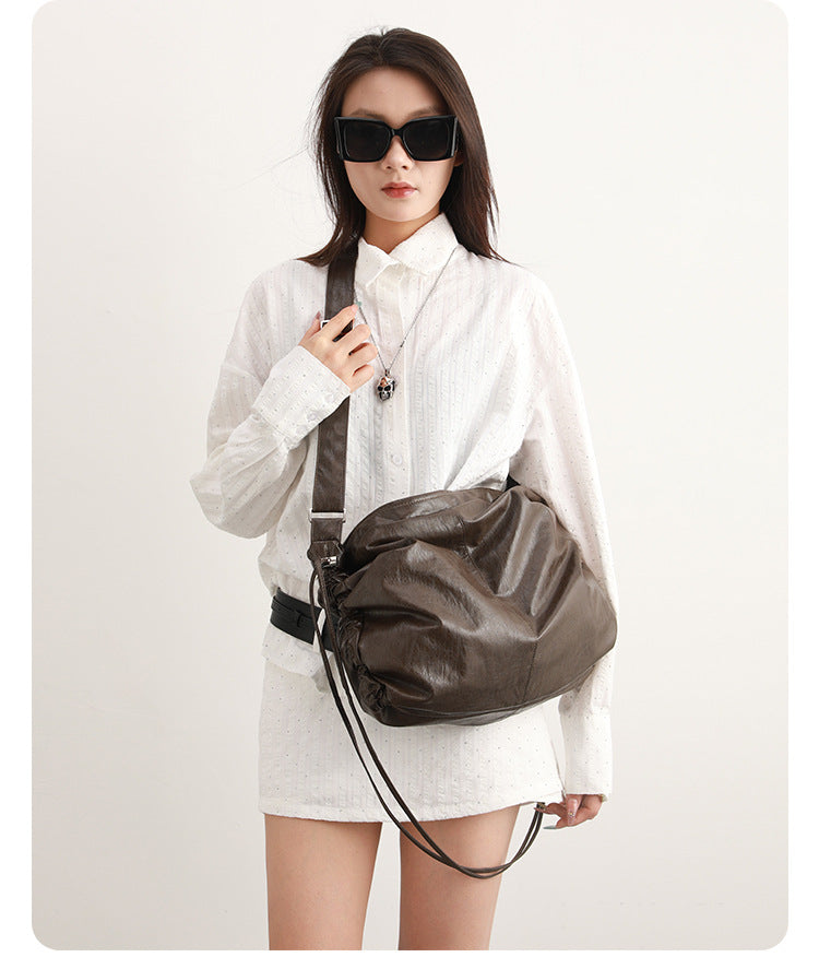 Oversized slouchy hobo shoulder bag with glossy crinkled leather-look finish, drawstring gathered sides, and silver-tone