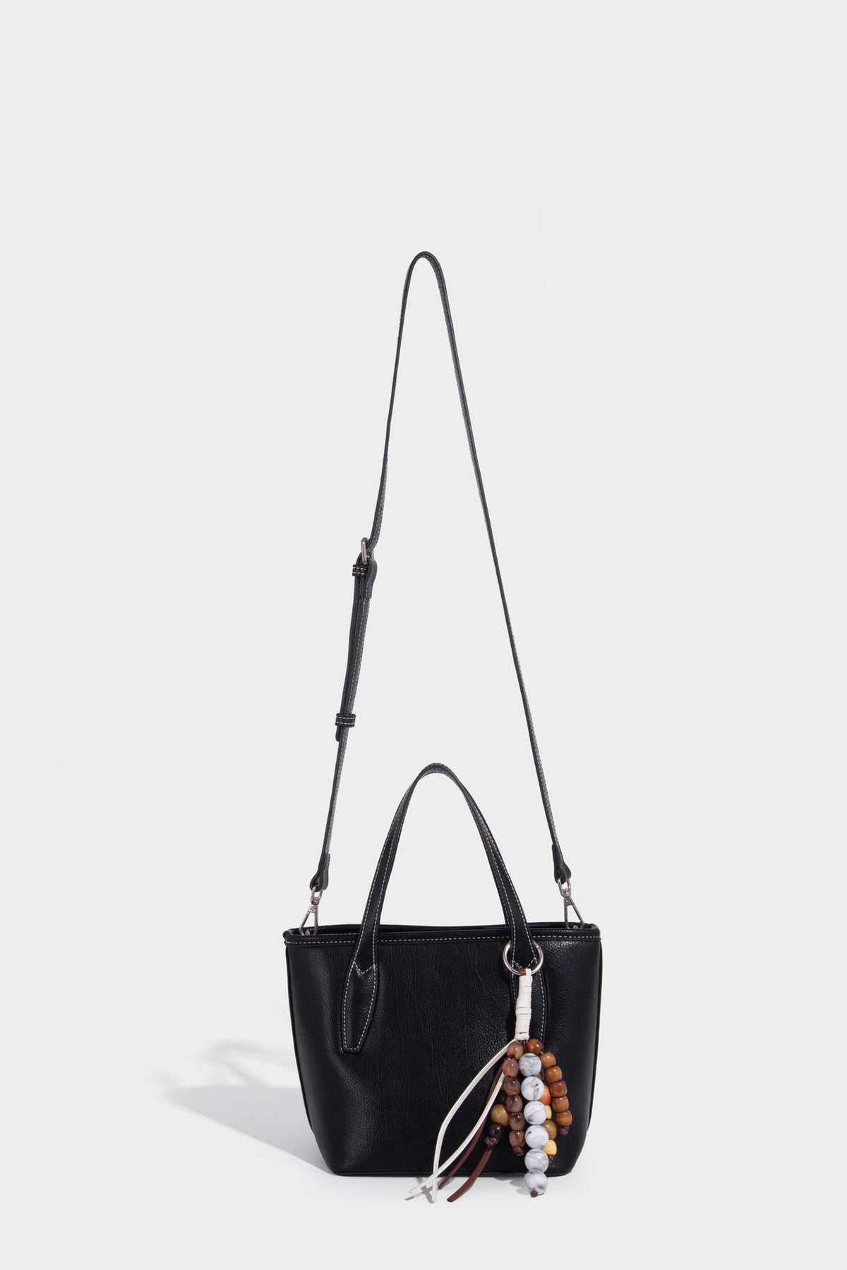 Compact structured bucket tote bag with pebbled textured finish, dual top handles, silver-tone lock hardware, and detachable