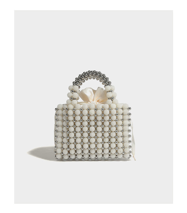Small boxy pearl-bead mini top-handle bag with silver metallic bead accents, satin floral detail, and long beaded shoulder
