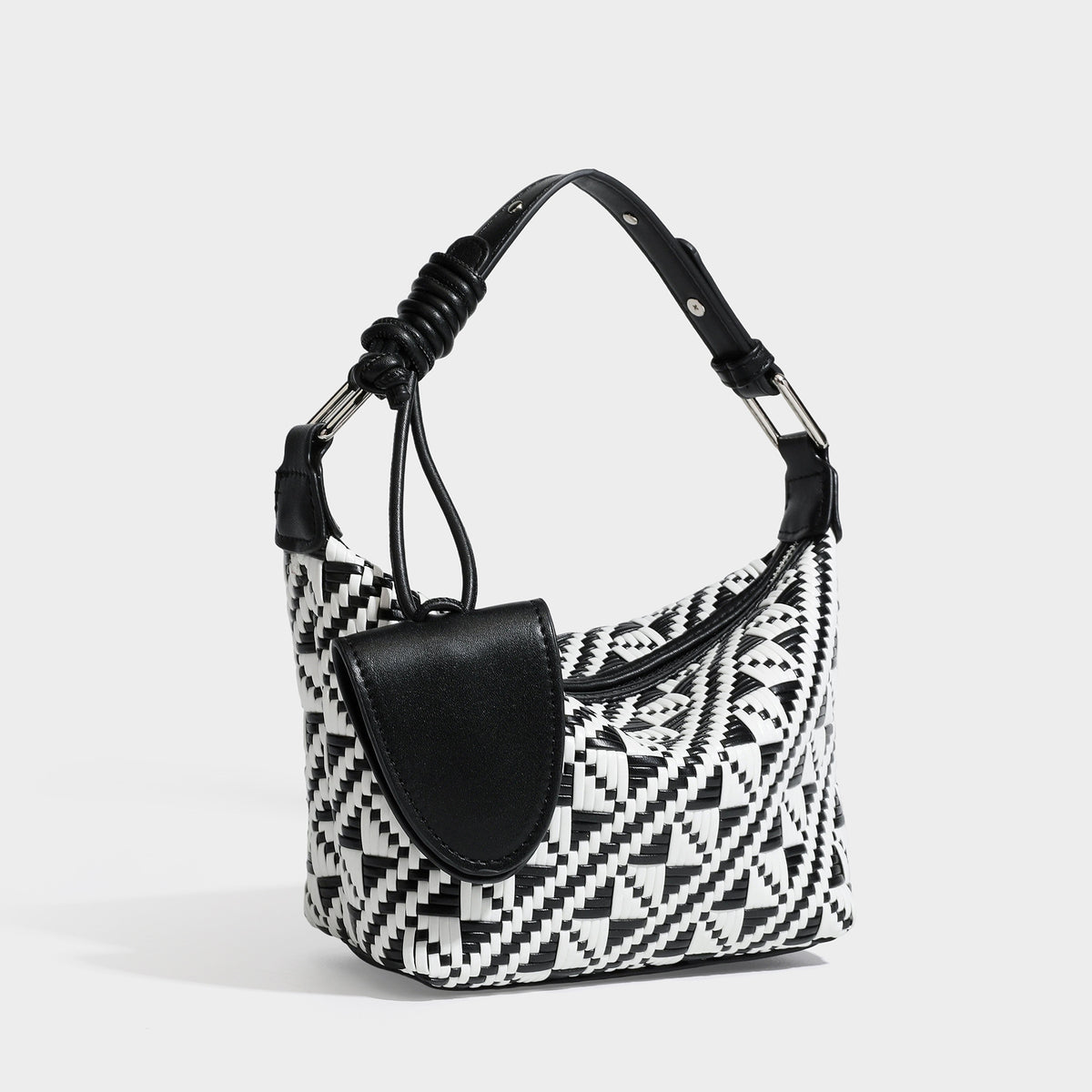 Kleine gewebte Schultertasche mit geometrischem Schwarz-Weiß-Muster, glatten dunkelbraunen Details in Lederoptik, geknotetem verstellbarem Riemen, Seitenansicht