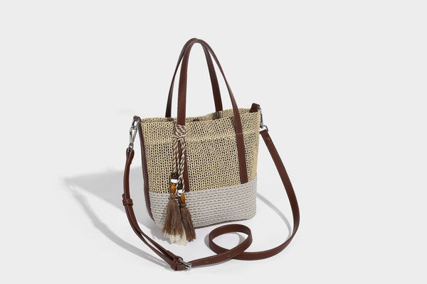 Two-tone open-weave tote bag in beige and cream with brown leather-look handles, tassel bead charm, and detachable