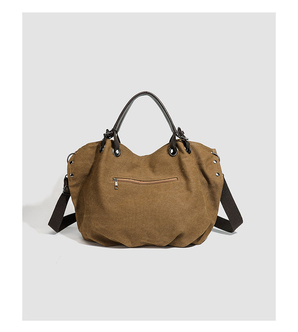 Slouchy matte canvas tote bag with dark dual top handles, metal grommet hardware, and detachable long shoulder strap, detail