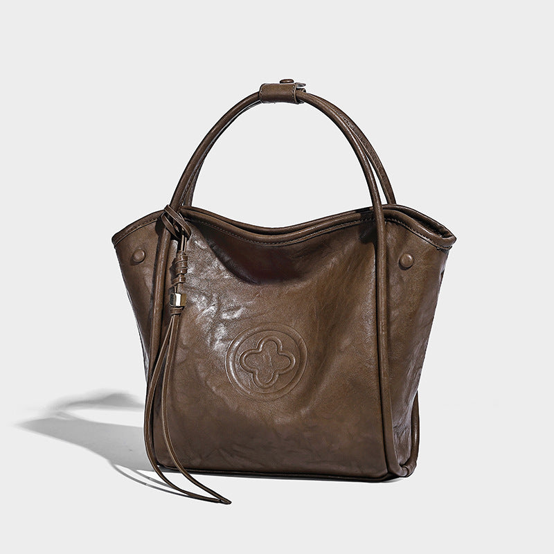 Glänzende Tote-Bag in geknautschter Lederoptik mit geprägtem Rundemblem, Quastenverschluss, zwei Tragegriffen und abnehmbarem