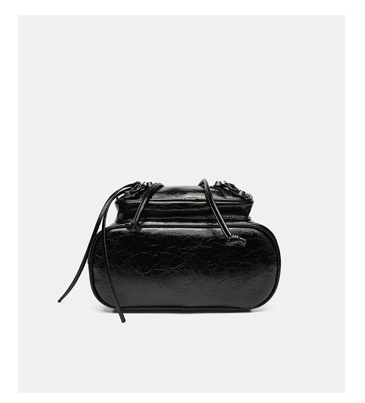 Small structured glossy leather-look convertible backpack handbag in black with flap closure, front zip pockets, metal stud