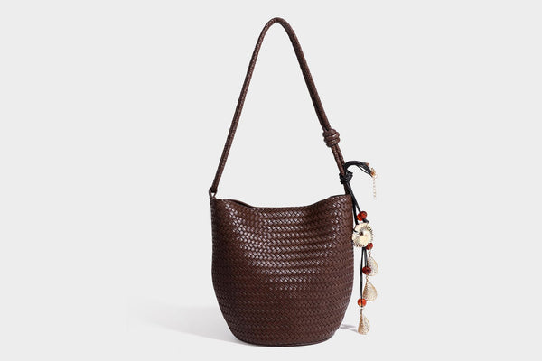 Olive green woven leather-look bucket bag with braided crossbody strap, knotted adjustment, and gold-tone tassel charm with