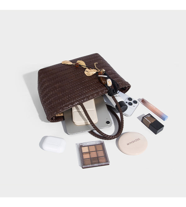 Structured chevron woven leather-look tote bag with braided top handles, gold feather charm, and adjustable shoulder strap