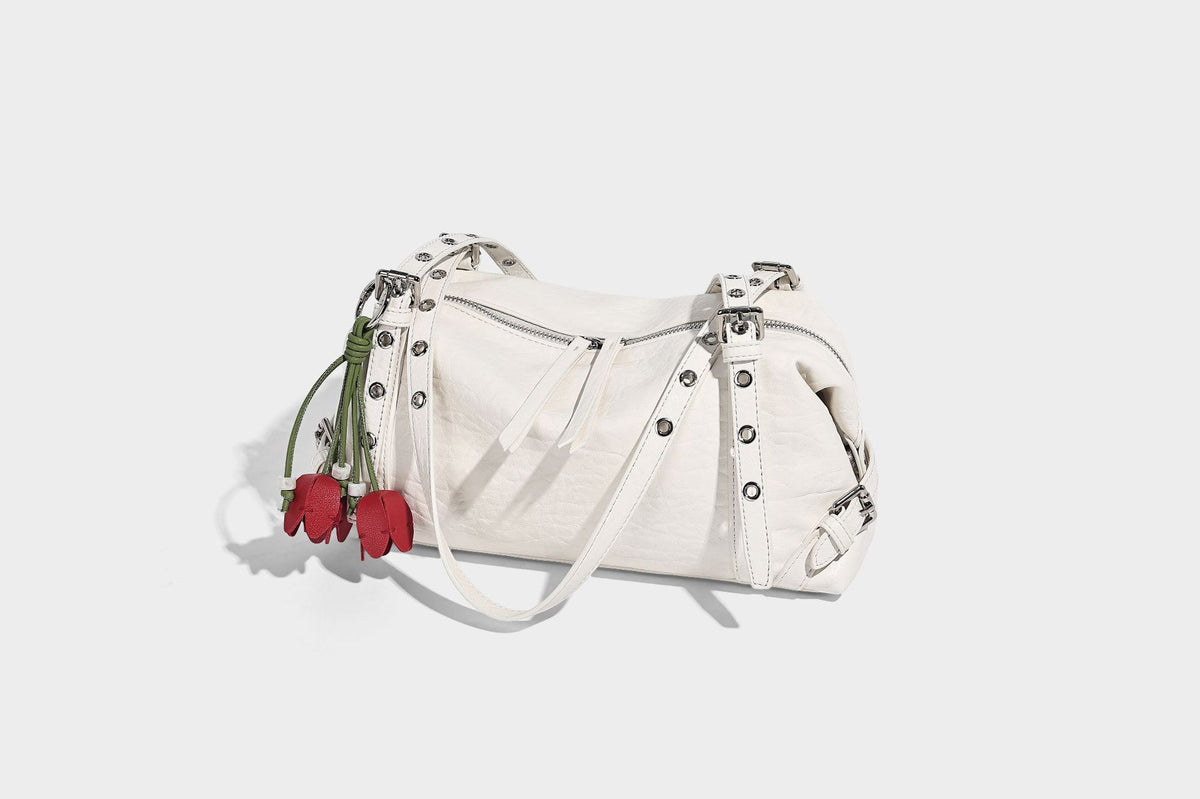 Pale yellow leather-look barrel bag with silver grommet-studded shoulder straps, top zip closure, and pink tulip floral