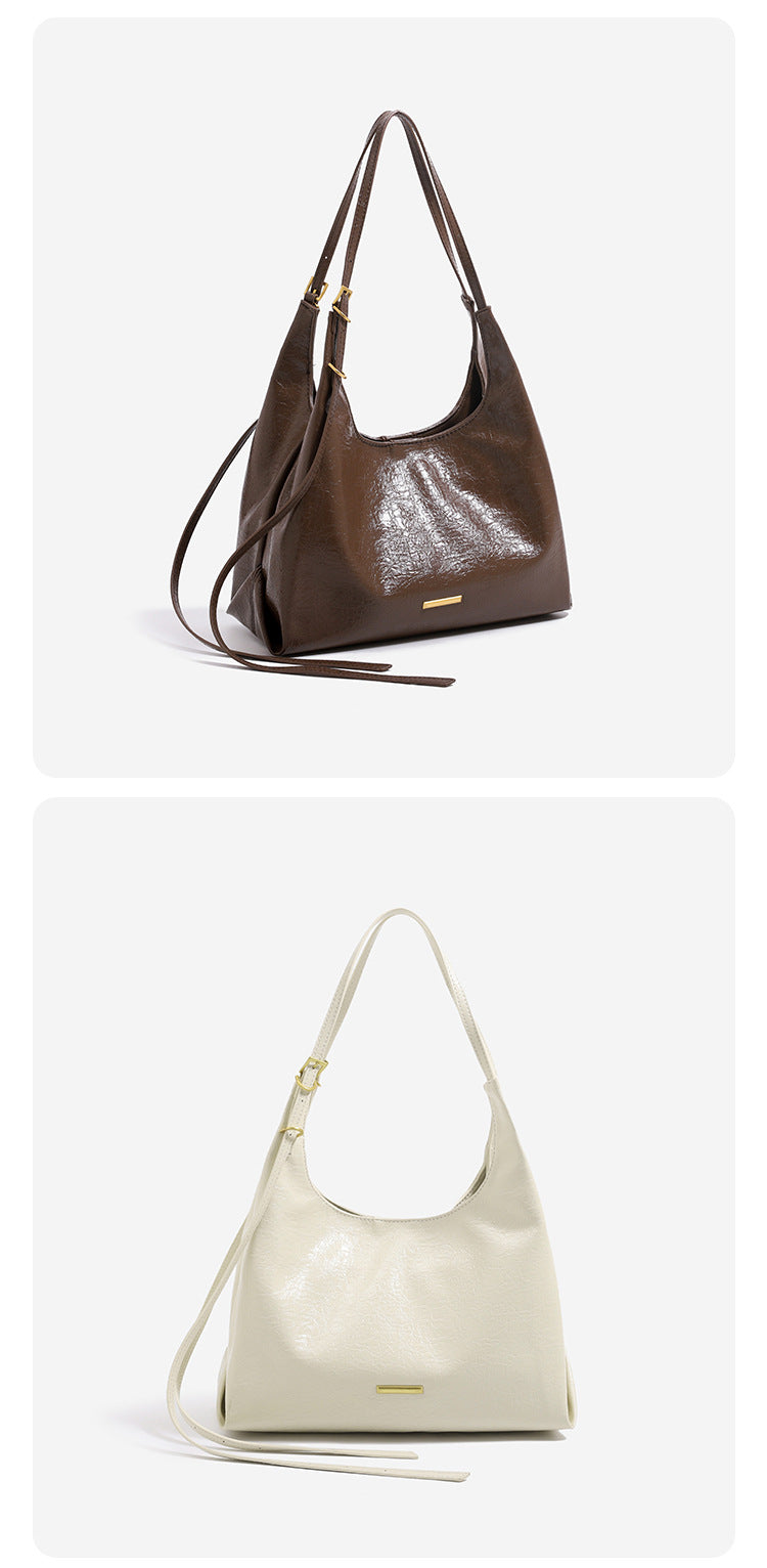 Slouchy hobo shoulder bag in crinkle high-gloss leather-look finish with gold-tone bar hardware and adjustable strap, detail