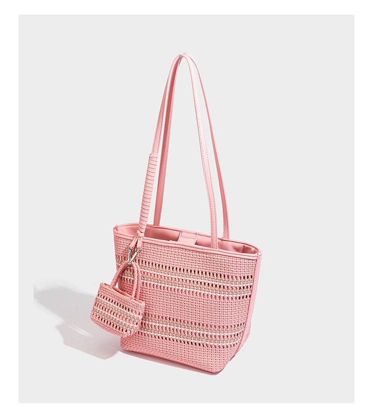 Large structured woven tote bag with striped basket-weave finish, long shoulder straps, and detachable mini pouch charm
