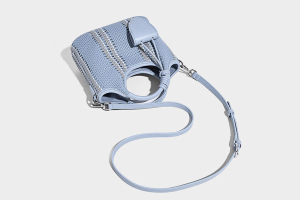 Geflochtene Bucket-Tasche in Pastellblau mit geflochtenen Henkeln, vorderem Einsteckfach, Perlenanhänger und abnehmbarem Schulterriemen