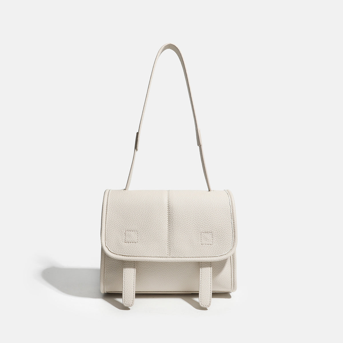 Compact structured flap satchel bag with pebbled texture, snap closure, front strap tabs, and long adjustable crossbody