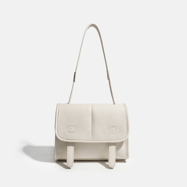 Compact structured flap satchel bag with pebbled texture, snap closure, front strap tabs, and long adjustable crossbody
