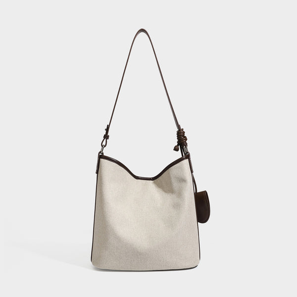 Cremefarbene Canvas-Beuteltasche mit dunkelbraunem Besatz in Lederoptik, geknotetem Riemen und befestigter Mini-Tasche, Detailansicht 3